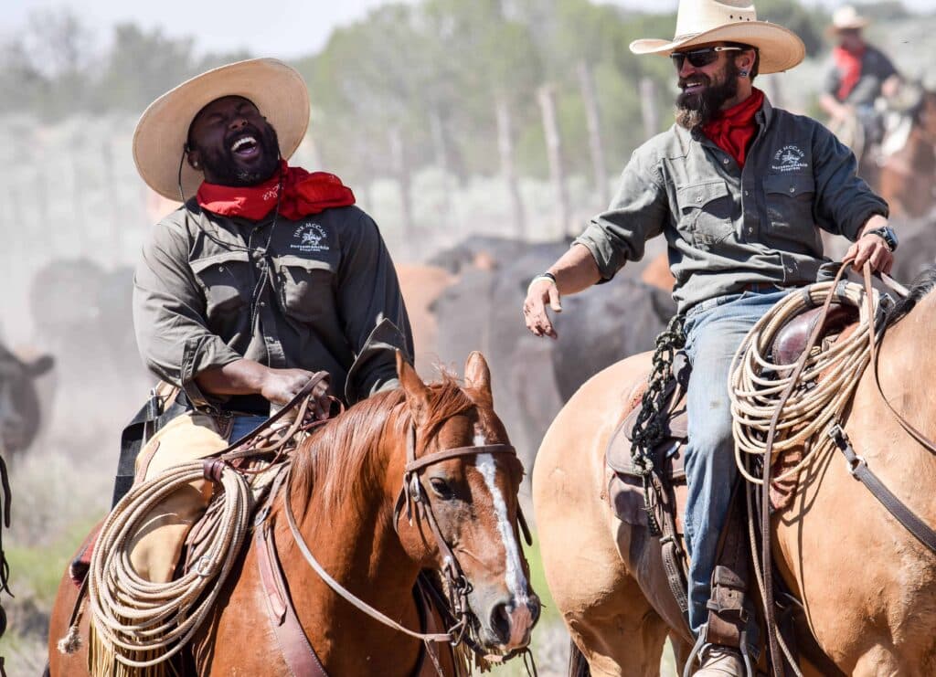 Service members laugh while riding horse at the Jinx McCain Horsemanship program